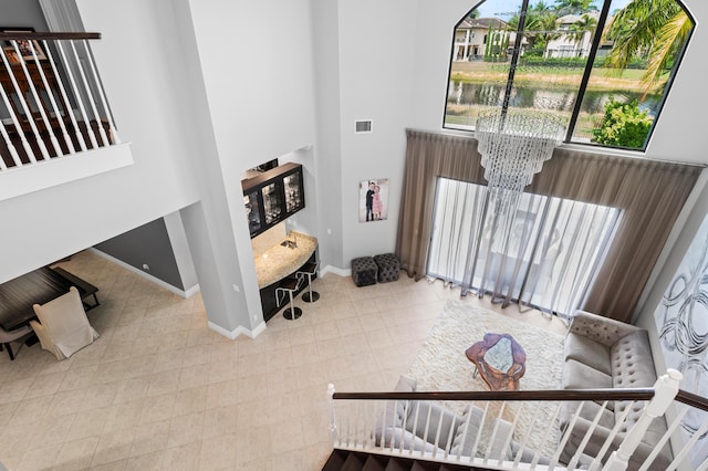 stairs with a high ceiling, a notable chandelier, baseboards, a water view, and visible vents