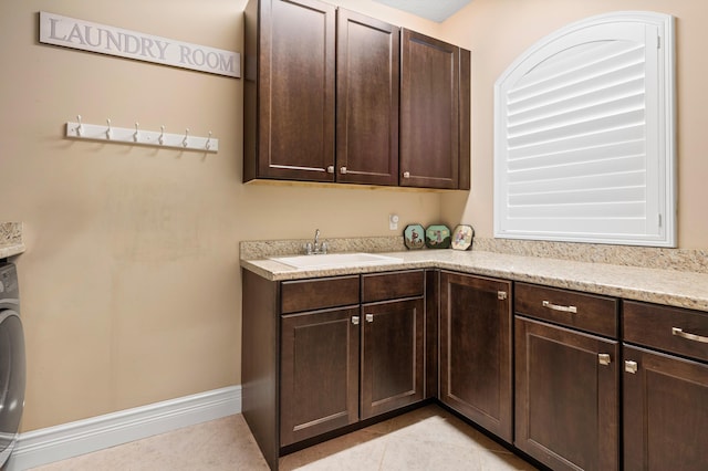 laundry room featuring washer / clothes dryer, cabinet space, light tile patterned floors, baseboards, and a sink