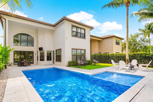 rear view of house featuring a fenced in pool, stucco siding, and a patio area