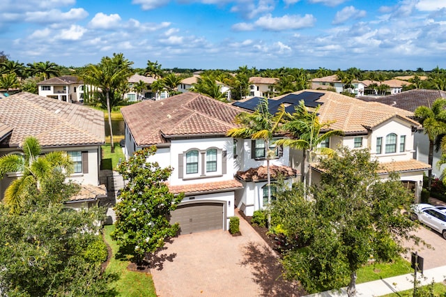 view of front of house with an attached garage, driveway, a residential view, and a tile roof