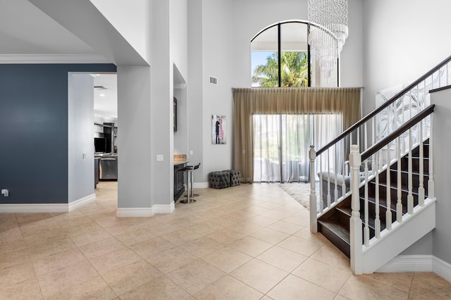 tiled foyer entrance with an inviting chandelier, ornamental molding, stairs, baseboards, and a high ceiling