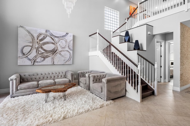 living area with baseboards, a towering ceiling, tile patterned flooring, and stairway