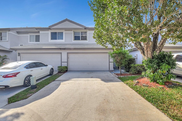 townhome / multi-family property with driveway, an attached garage, and stucco siding
