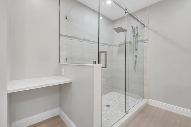 full bath featuring wood finished floors, a stall shower, and baseboards