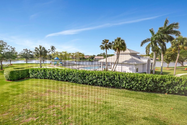 view of yard featuring fence, playground community, a water view, and a fenced in pool