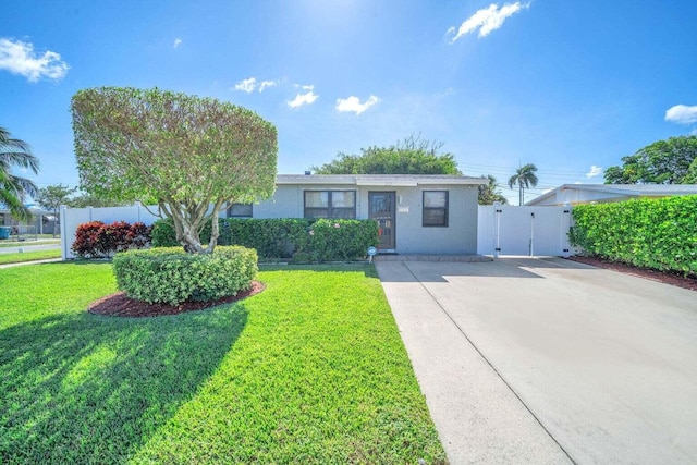 ranch-style home featuring a gate, driveway, a front yard, and stucco siding