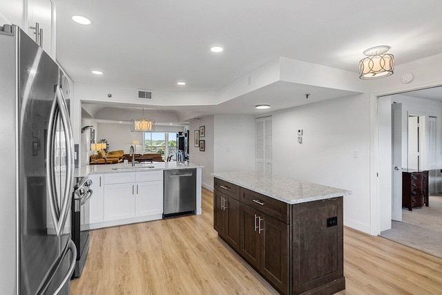 kitchen featuring a sink, visible vents, stainless steel appliances, dark brown cabinets, and light wood finished floors