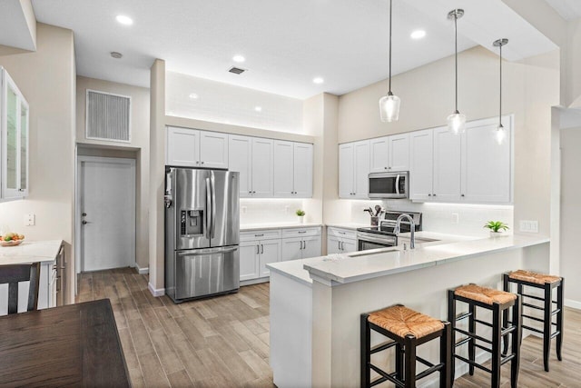kitchen featuring a peninsula, appliances with stainless steel finishes, a kitchen breakfast bar, and light wood finished floors