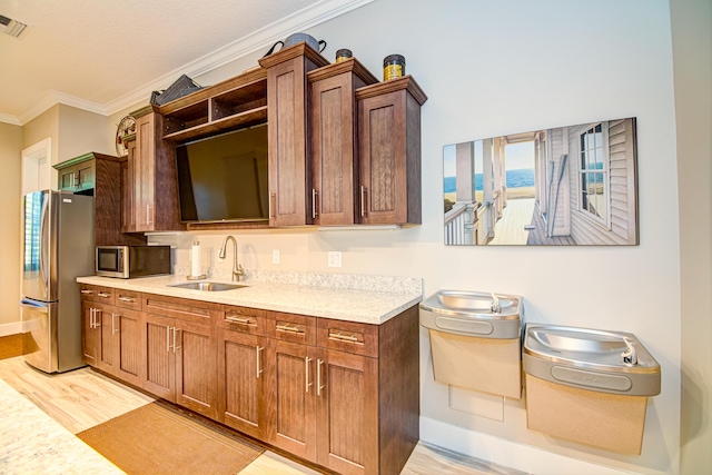 15688 Italian Cypress Way, Wellington, FL 33414 - kitchen featuring appliances with stainless steel finishes, a sink, light countertops, light wood-style floors, and ornamental molding