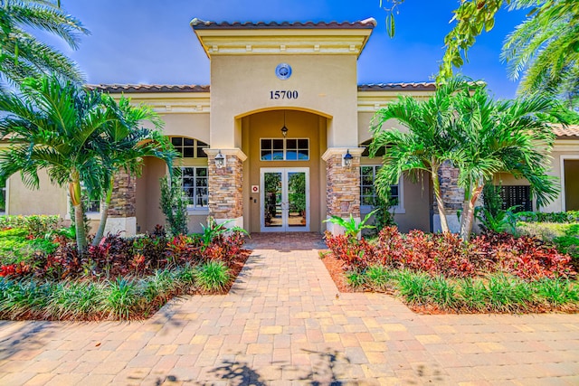 15688 Italian Cypress Way, Wellington, FL 33414 - property entrance with a tiled roof, stucco siding, french doors, and stone siding