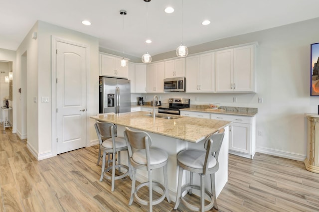 kitchen with baseboards, white cabinets, a sink, light wood-style flooring, and stainless steel appliances