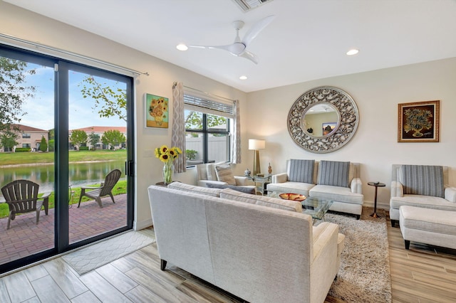 living room with recessed lighting, a ceiling fan, light wood finished floors, and a water view