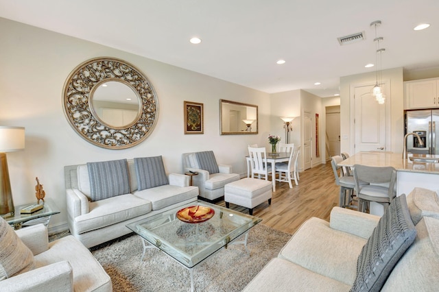 living area with baseboards, light wood finished floors, recessed lighting, and visible vents