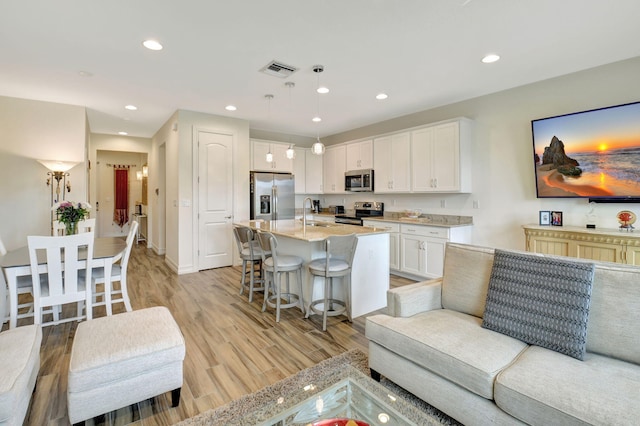 living area featuring visible vents, recessed lighting, light wood-style flooring, and baseboards