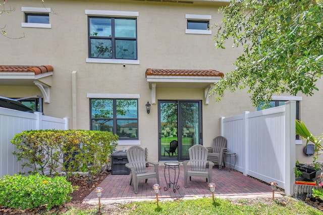 back of property featuring fence, a tile roof, a patio area, and stucco siding