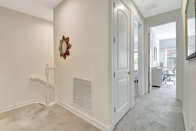 hallway featuring visible vents, carpet flooring, baseboards, and an upstairs landing