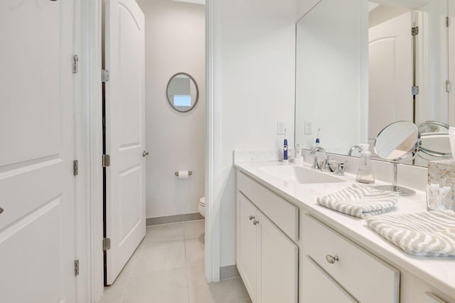 bathroom featuring toilet, baseboards, and vanity