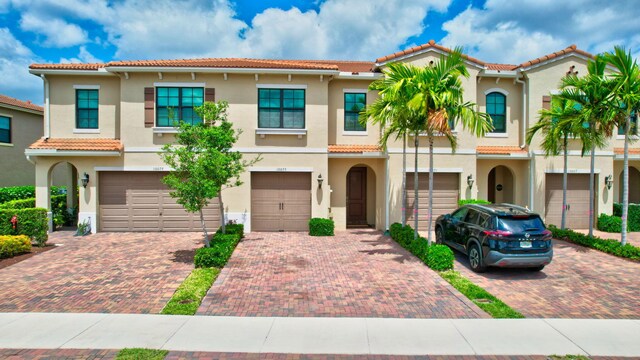 view of front of house featuring an attached garage, stucco siding, driveway, and a tile roof