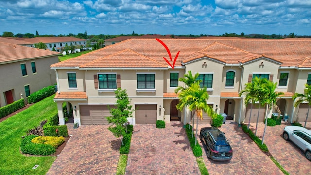 mediterranean / spanish house featuring a tiled roof, an attached garage, driveway, and stucco siding