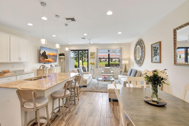 kitchen featuring white cabinets, recessed lighting, light stone counters, and a sink