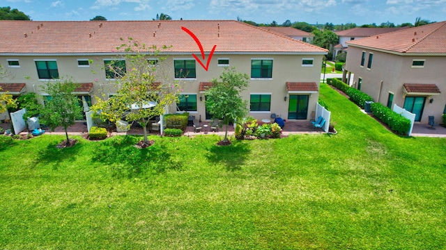 rear view of house featuring a lawn, a patio area, stucco siding, and a tile roof