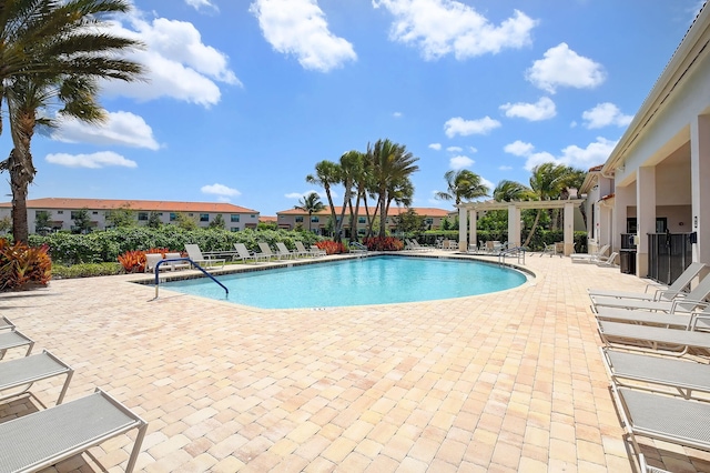 community pool featuring a patio, a pergola, and a residential view