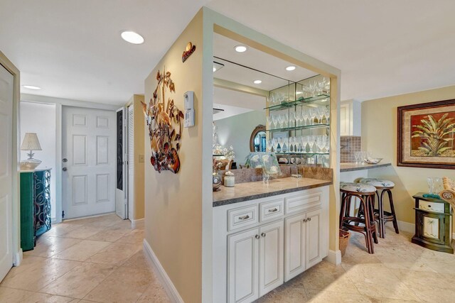 bar with recessed lighting, baseboards, decorative backsplash, light tile patterned floors, and indoor bar