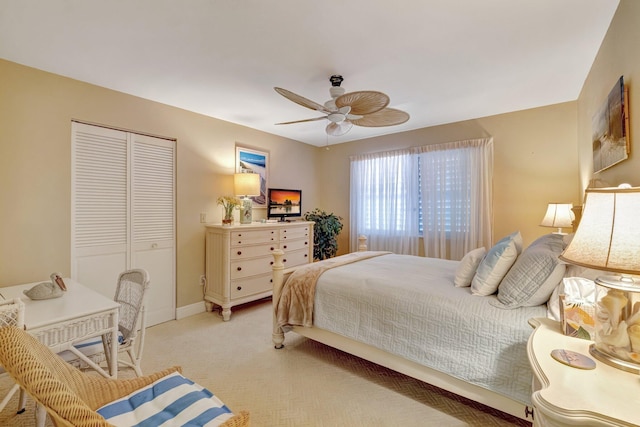 bedroom featuring baseboards, a ceiling fan, a closet, and light colored carpet