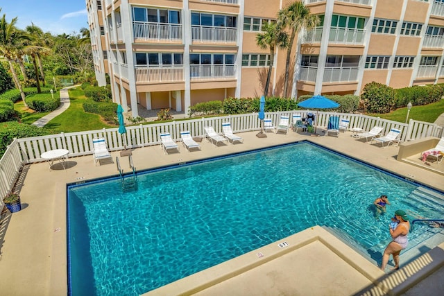 community pool with a patio area and fence