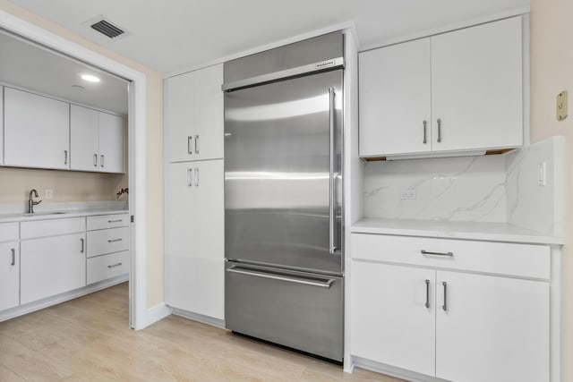 kitchen with visible vents, a sink, built in fridge, and light countertops