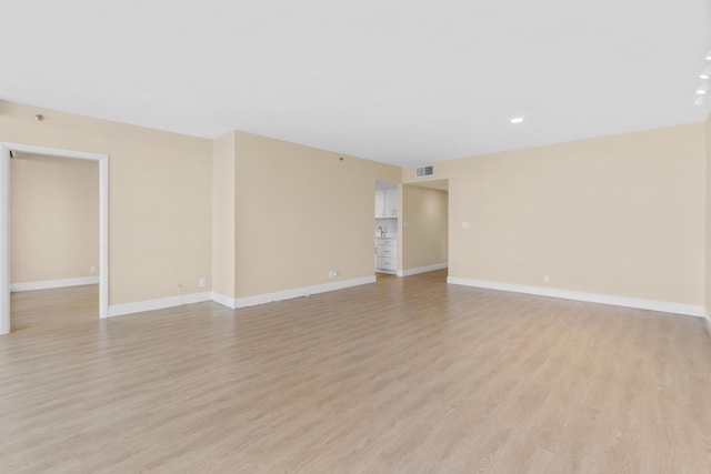 empty room featuring visible vents, light wood-style flooring, and baseboards