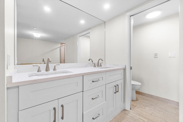 full bathroom featuring double vanity, toilet, a sink, and wood finished floors