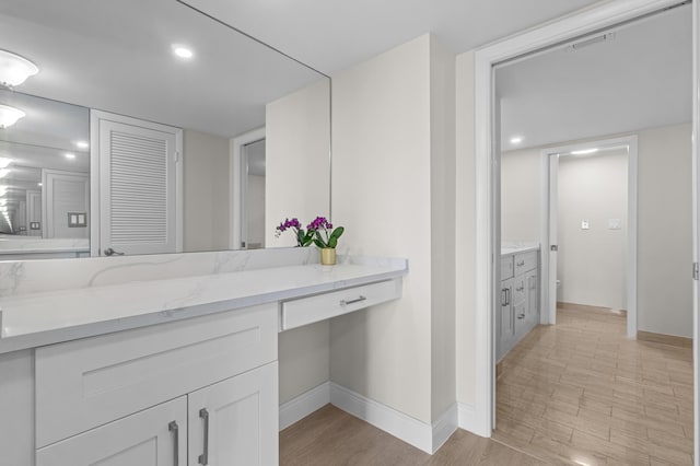 bathroom with recessed lighting, baseboards, wood finished floors, and vanity
