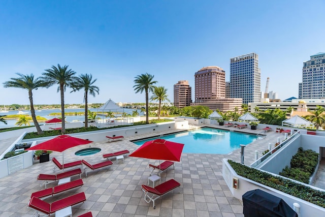 pool with a view of city, a water view, a community hot tub, and a patio area