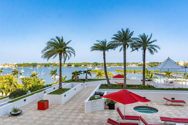 view of patio / terrace with a water view, an in ground hot tub, and fence