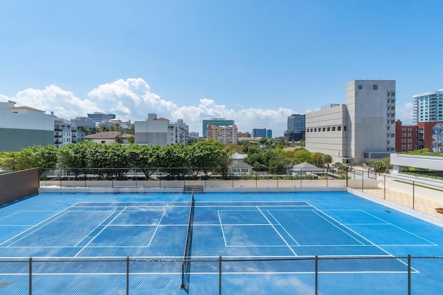 view of tennis court with fence and a view of city