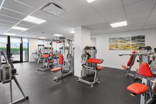 gym featuring baseboards and a drop ceiling