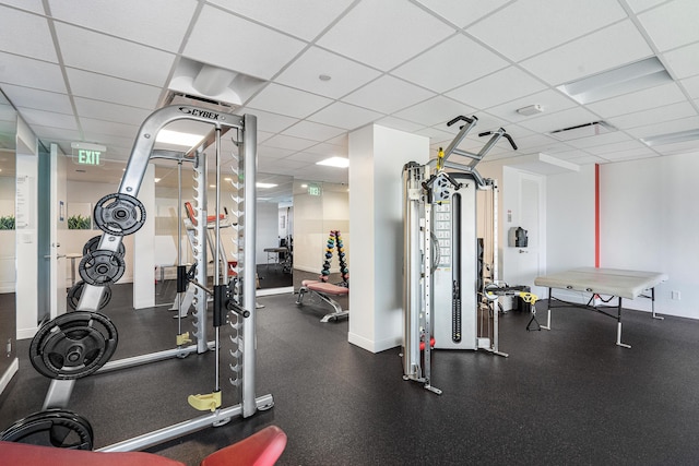 exercise room with baseboards and a drop ceiling
