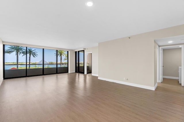 unfurnished living room with recessed lighting, baseboards, floor to ceiling windows, and wood finished floors