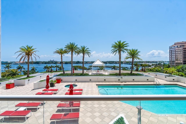 community pool with a gazebo, a water view, and a patio area