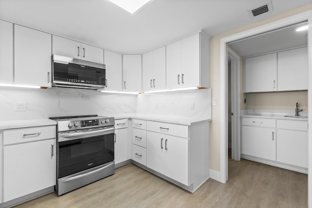 kitchen with stainless steel appliances, visible vents, decorative backsplash, and light wood-style flooring