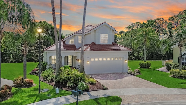 view of front of house featuring a front lawn, a tile roof, a garage, stucco siding, and driveway