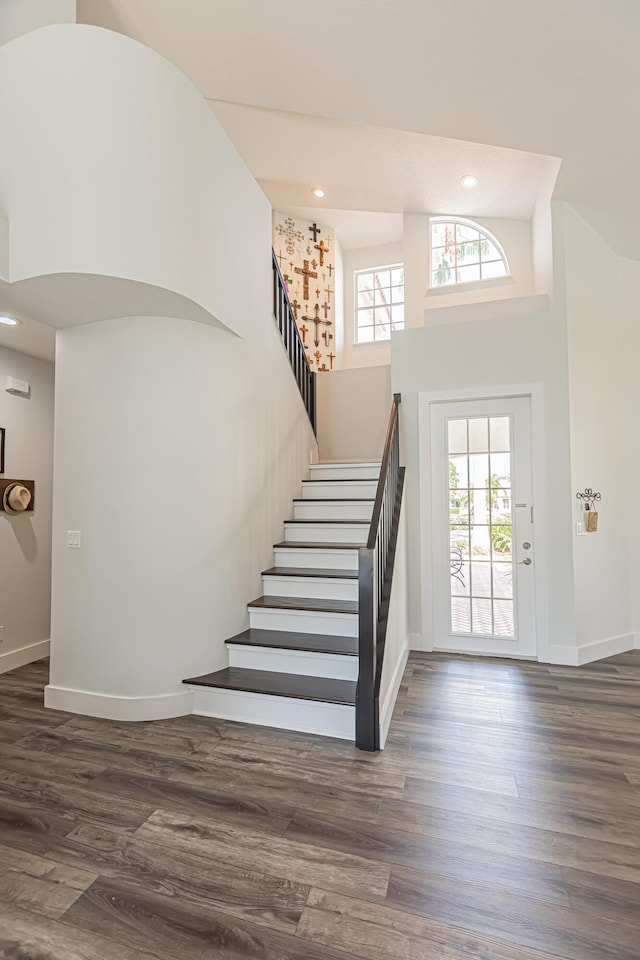foyer featuring stairs, a high ceiling, baseboards, and wood finished floors