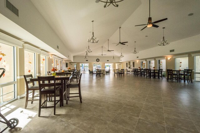 dining room with high vaulted ceiling, visible vents, and ceiling fan with notable chandelier