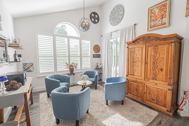 living area featuring high vaulted ceiling, baseboards, wood finished floors, and a chandelier