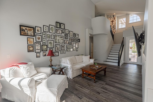 living area with high vaulted ceiling, baseboards, stairs, and wood finished floors