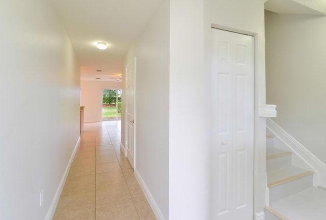 corridor with baseboards, stairway, and light tile patterned floors