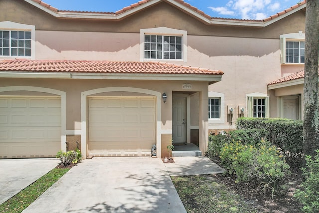 mediterranean / spanish-style house featuring stucco siding, a tile roof, driveway, and an attached garage