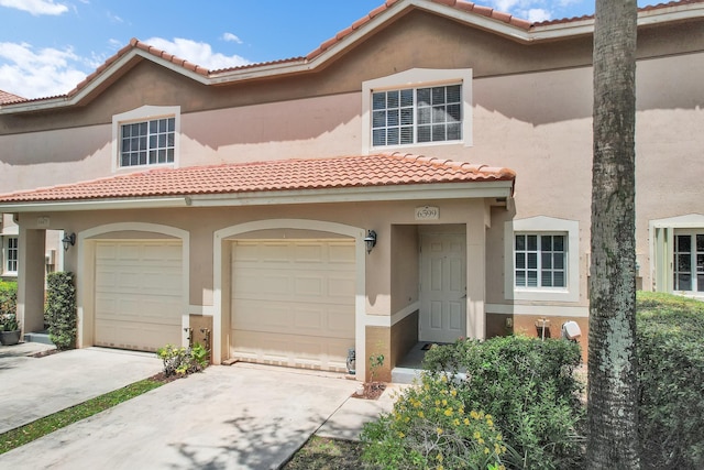 view of front of property with stucco siding, a tile roof, a garage, and concrete driveway