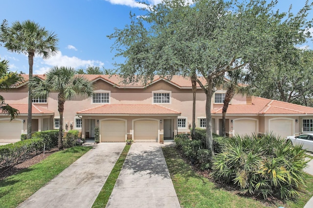 view of front of house with a garage, a tile roof, concrete driveway, and stucco siding